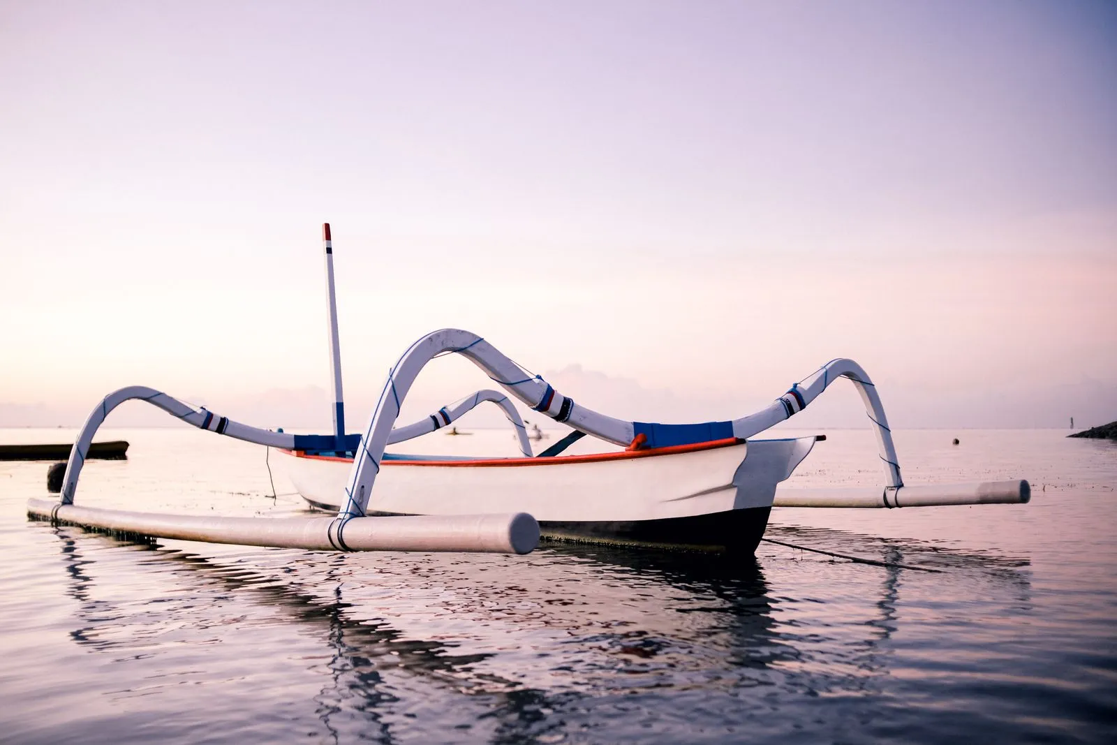A jukung outrigger on flat water at first light