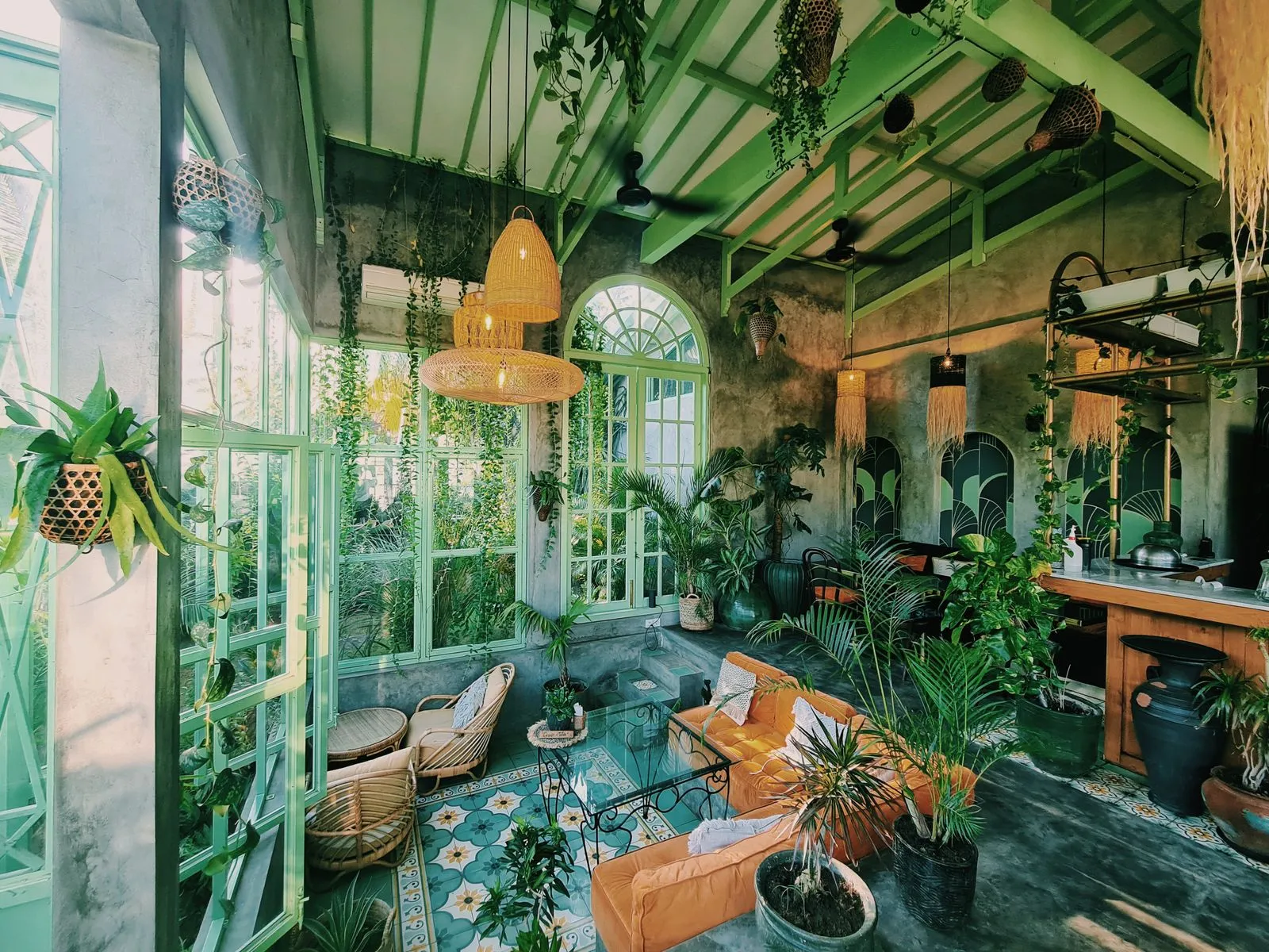 A plant-filled cafe interior with rattan lights and no people