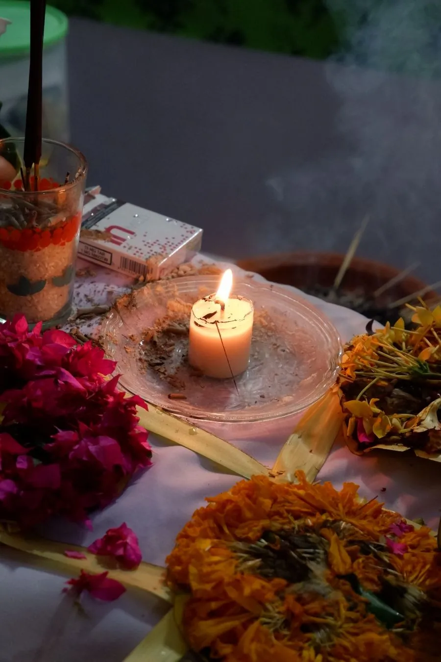 A canang sari offering with marigolds and a lit candle